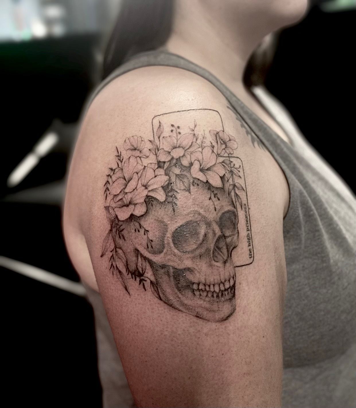 A woman has a tattoo of a skull with flowers on it