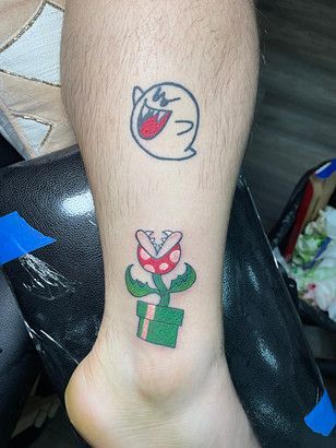 A person has a tattoo of a ghost and a piranha plant on their leg.
