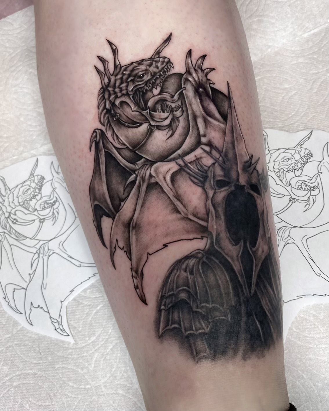 A tattoo of a dragon and a skull on a person 's leg