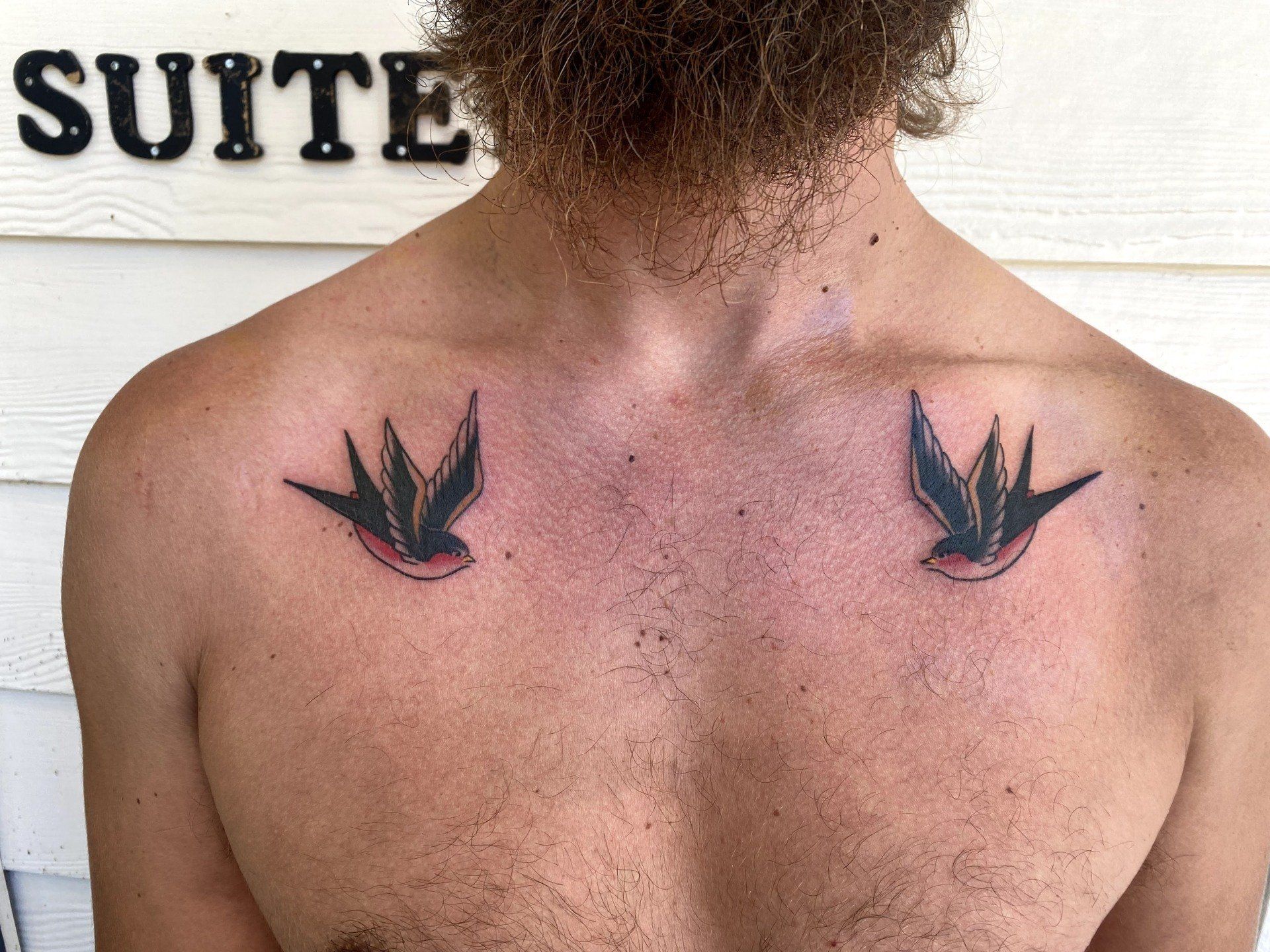 A man has two swallows tattooed on his chest