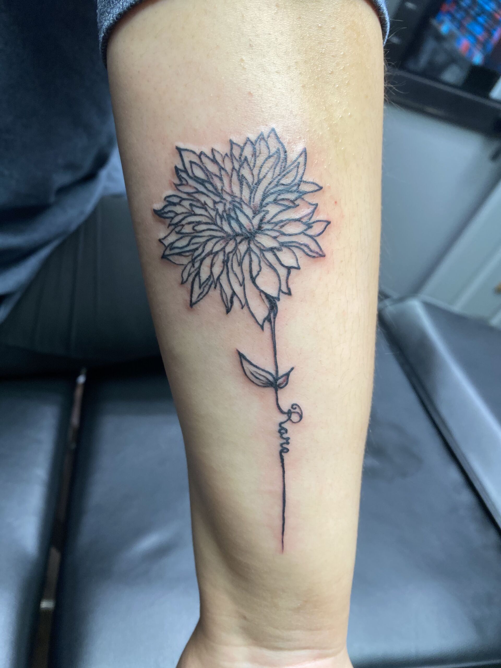 A woman has a tattoo of a flower on her forearm