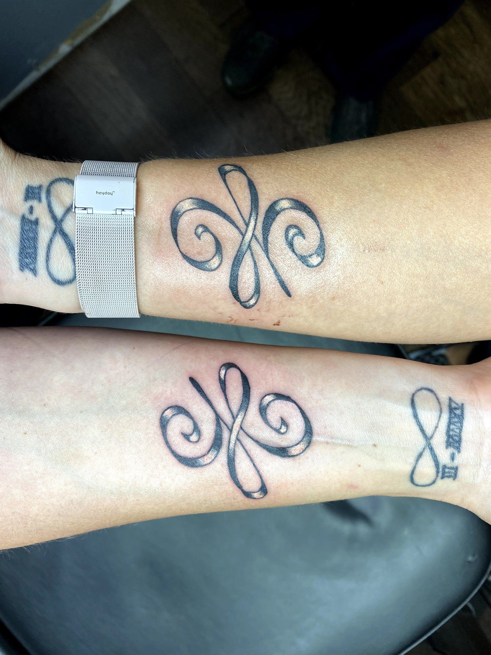 Two people have matching tattoos on their wrists