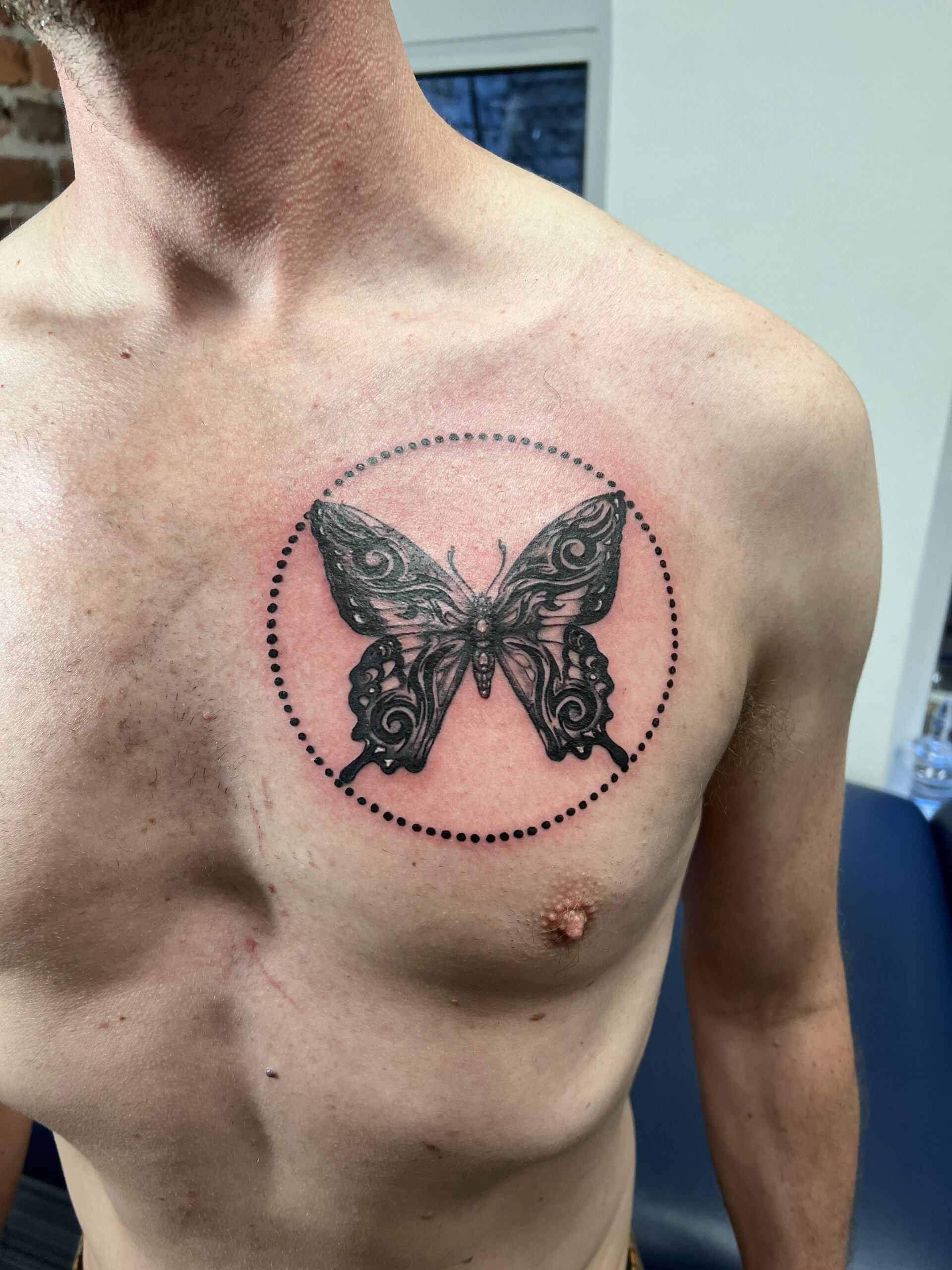 A man has a butterfly tattoo on his chest