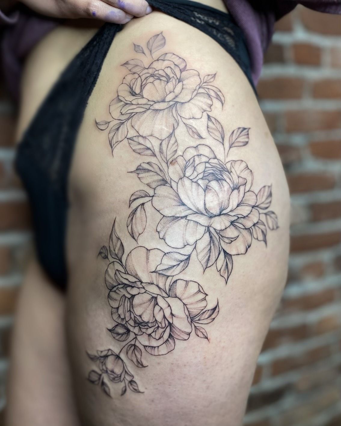 A woman has a tattoo of flowers on her thigh.