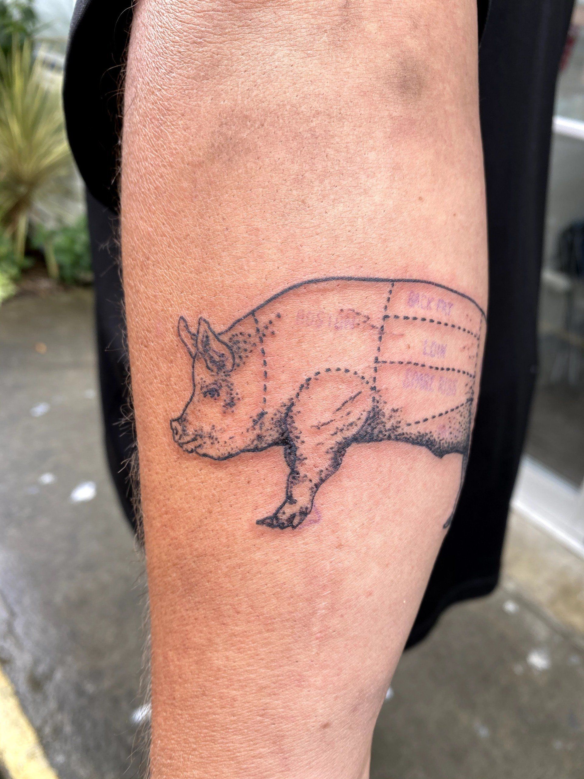 A person has a tattoo of a pig on their arm