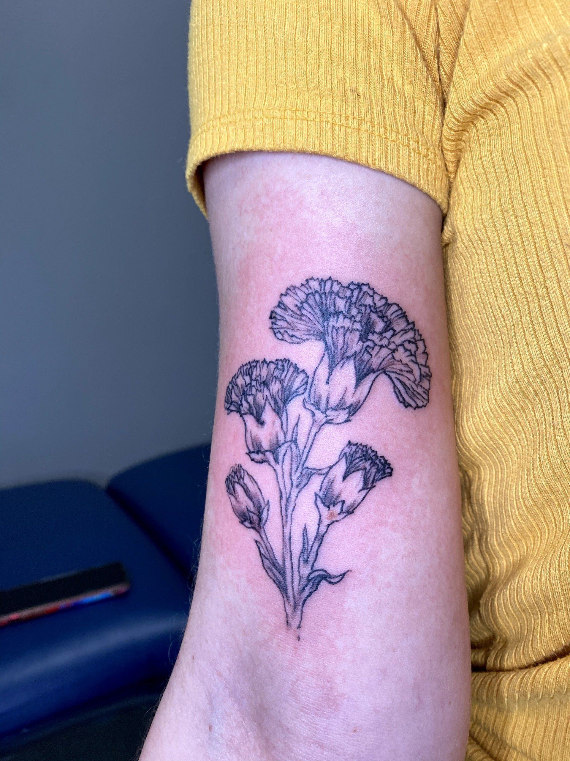 A person has a tattoo of flowers on their arm