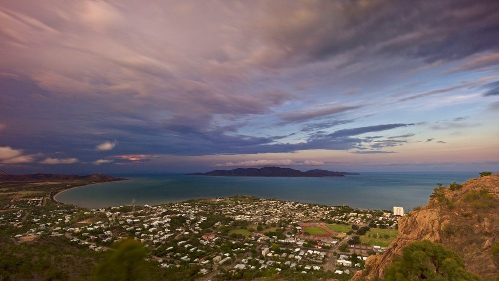 A View of a City From a Cliff Overlooking the Ocean at Sunset — V.I.P. Plastic Fabrication in Townsville, QLD