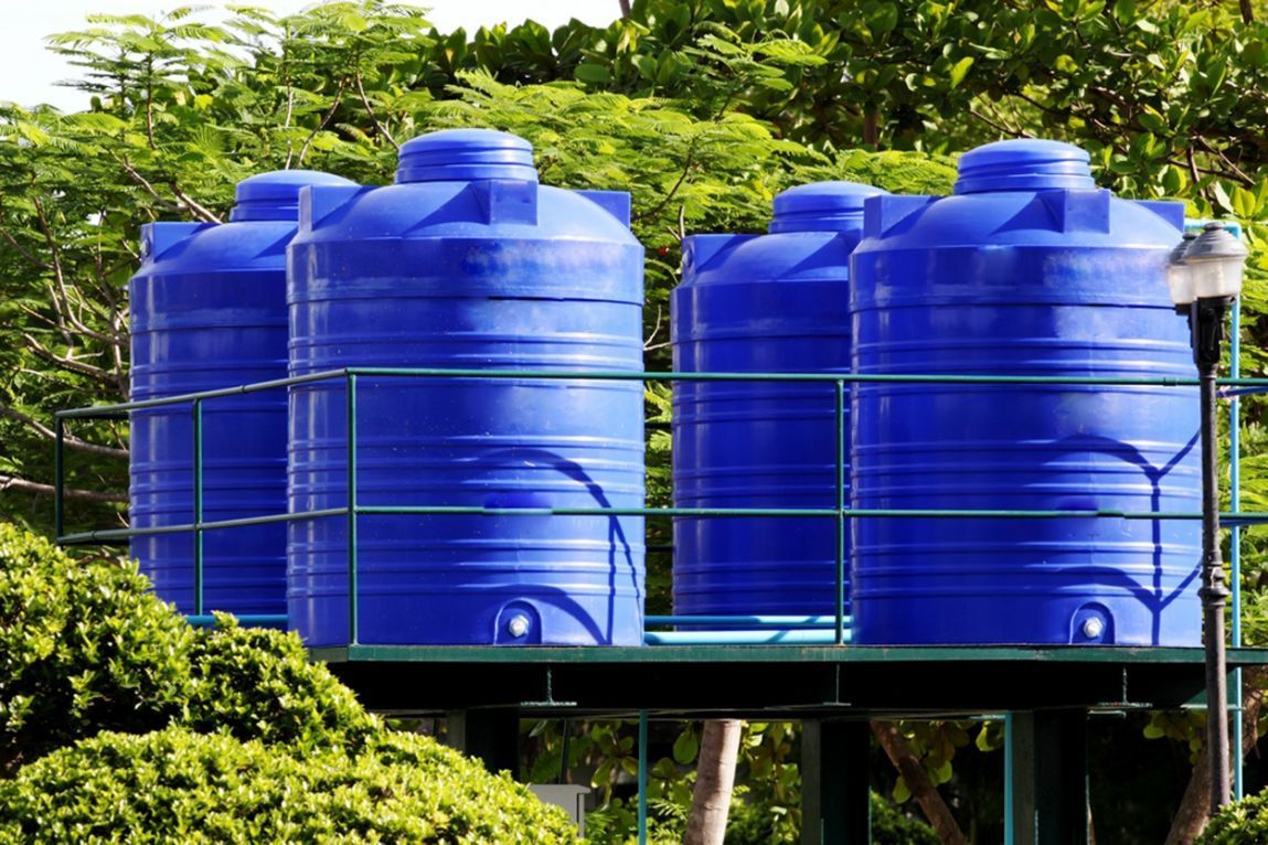 A Row of Blue Water Tanks Are Sitting on Top of a Green Platform — V.I.P. Plastic Fabrication in Cairns, QLD