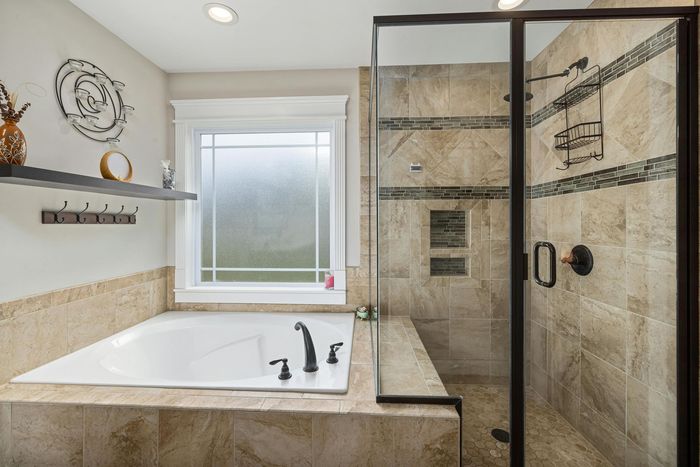 White bathtub facing the window and a shower section on the right.