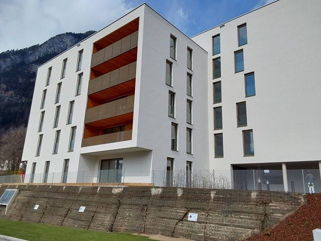 Ein großes weißes Gebäude mit Balkonen und Bergen im Hintergrund