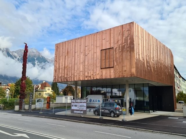 Ein großes Gebäude mit einer Kupferfassade und Bergen im Hintergrund