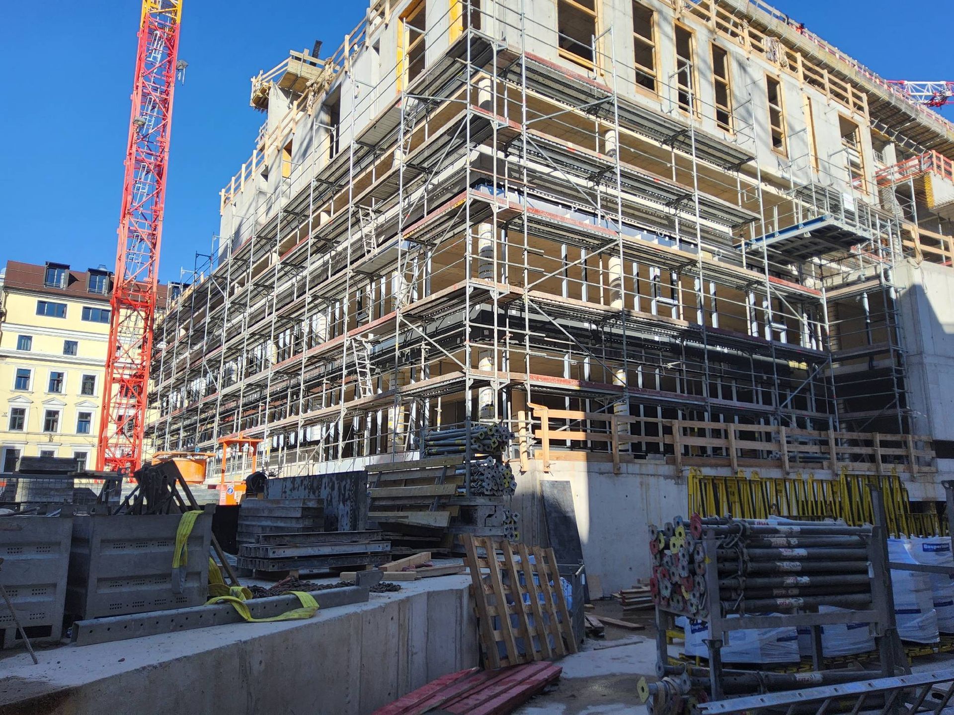 Ein großes Gebäude im Bau mit Gerüsten und einem Kran im Hintergrund.