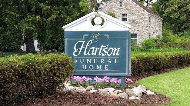 Sign for Hartson Funeral Home with building in background.