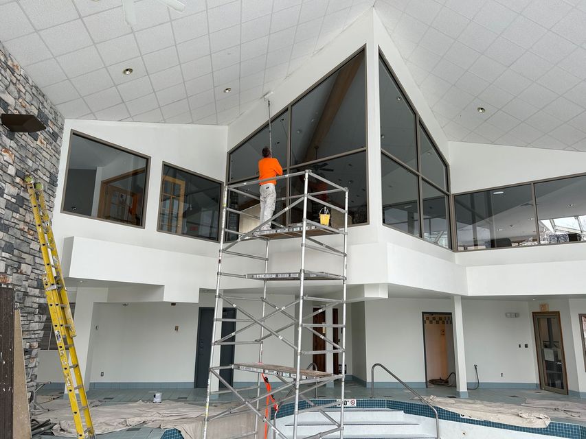 Two men are painting the ceiling of a living room.