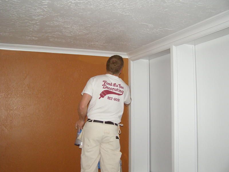 A man wearing a shirt that says rock the wall decorating