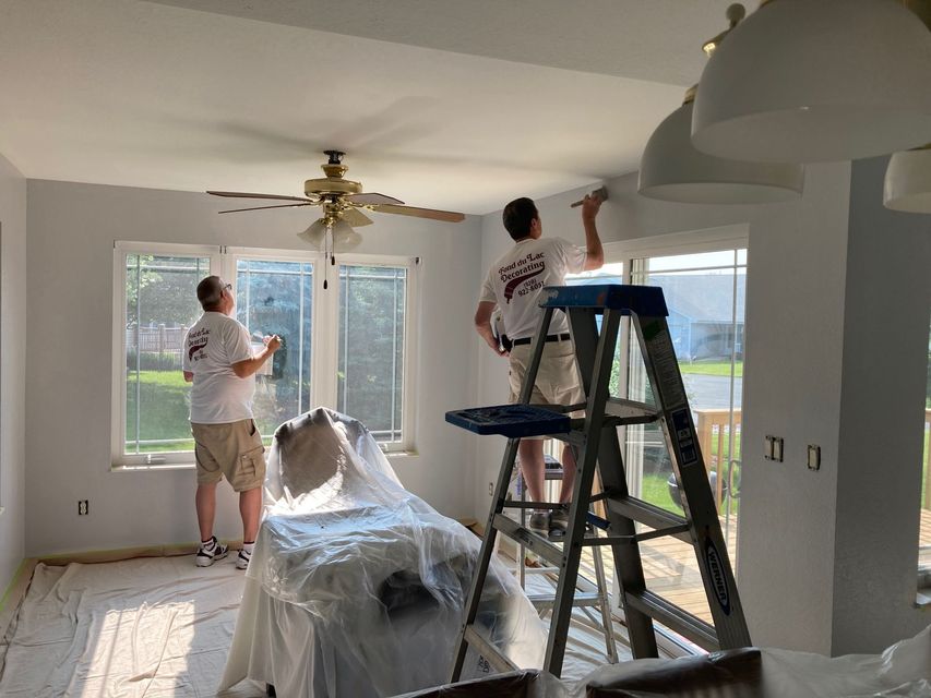 Two men are painting the ceiling of a living room.