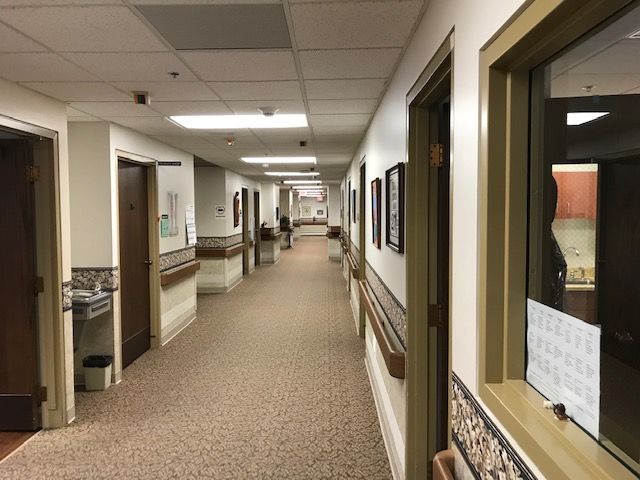 A long hallway in a hospital with many doors and a window