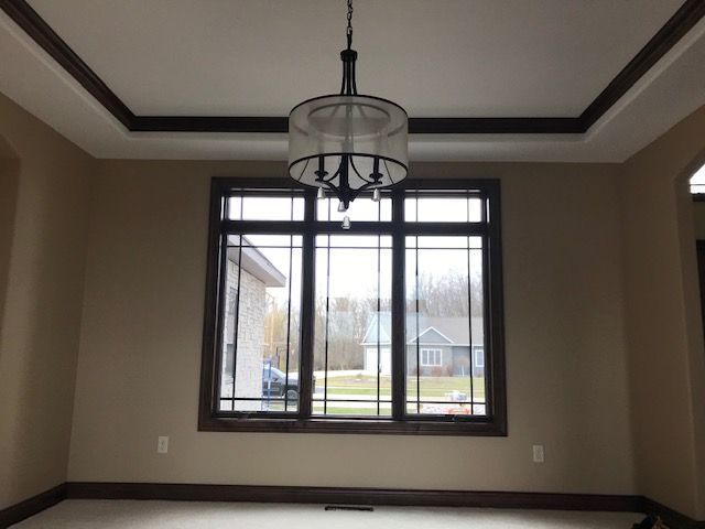 An empty room with a large window and a chandelier hanging from the ceiling