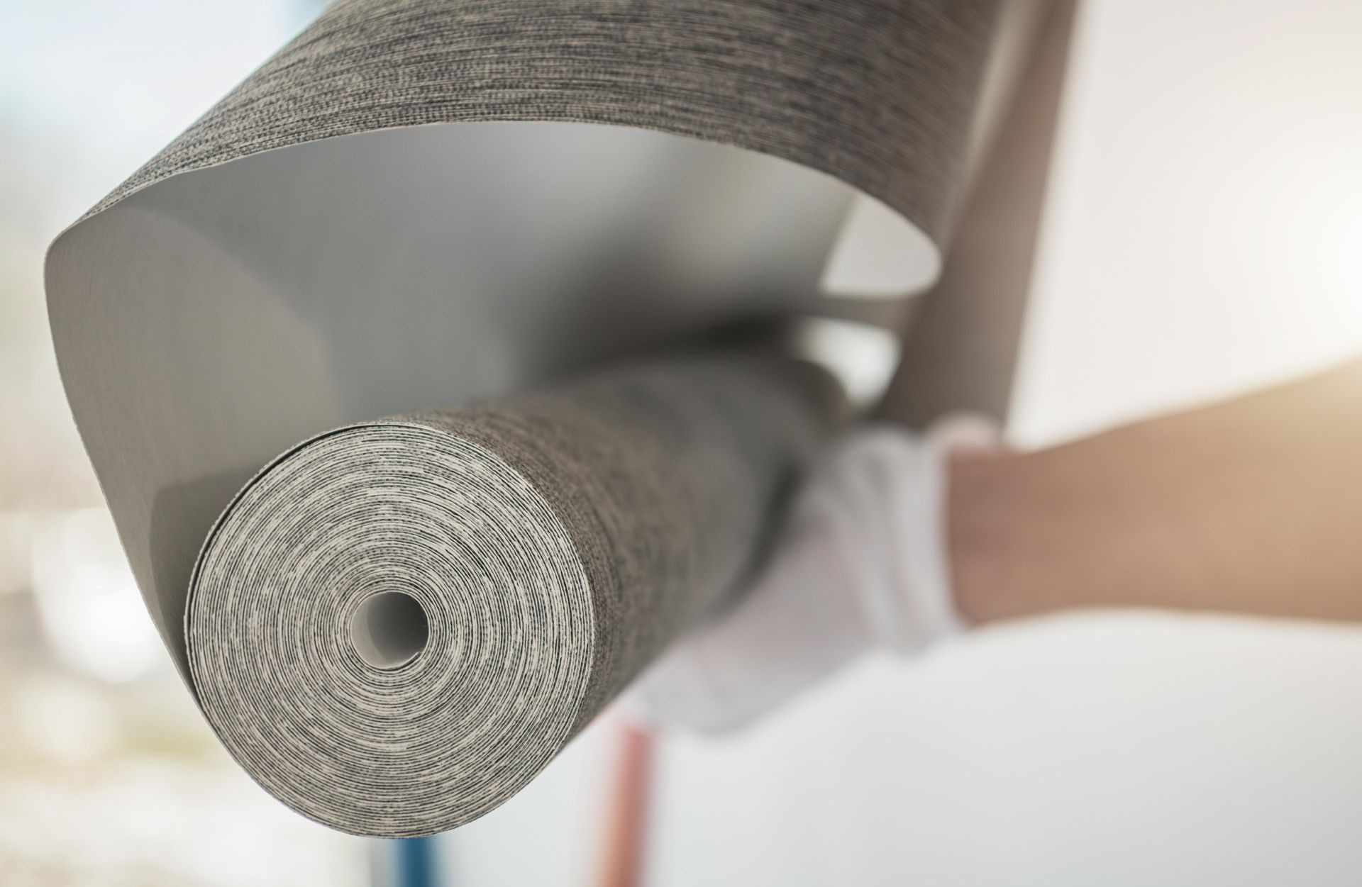 A person is holding a roll of wallpaper with a hole in the middle.