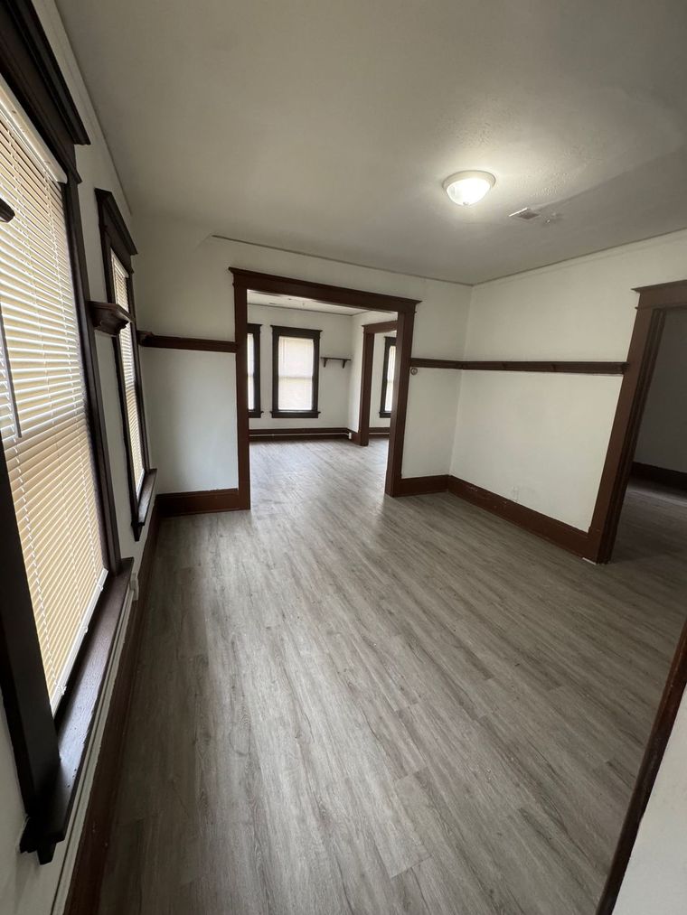An empty living room with hardwood floors and white walls.