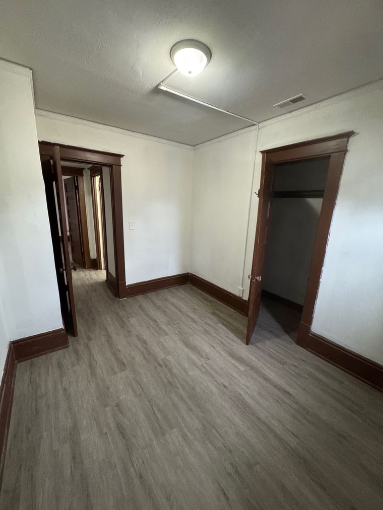 An empty room with hardwood floors and a light on the ceiling.