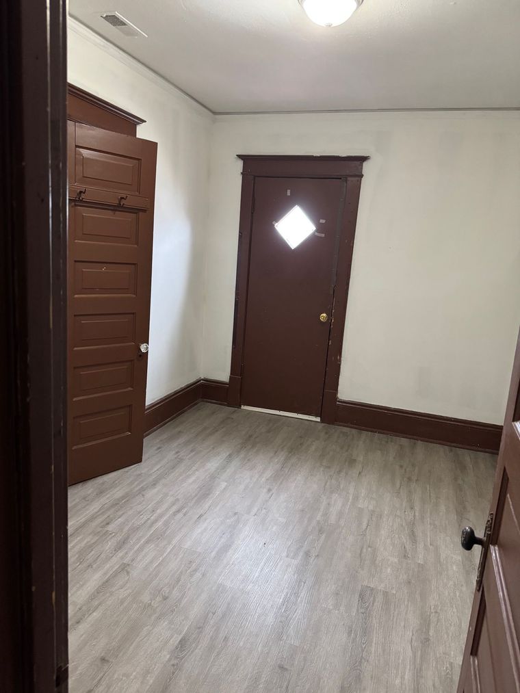 A room with a brown door and a white wall.