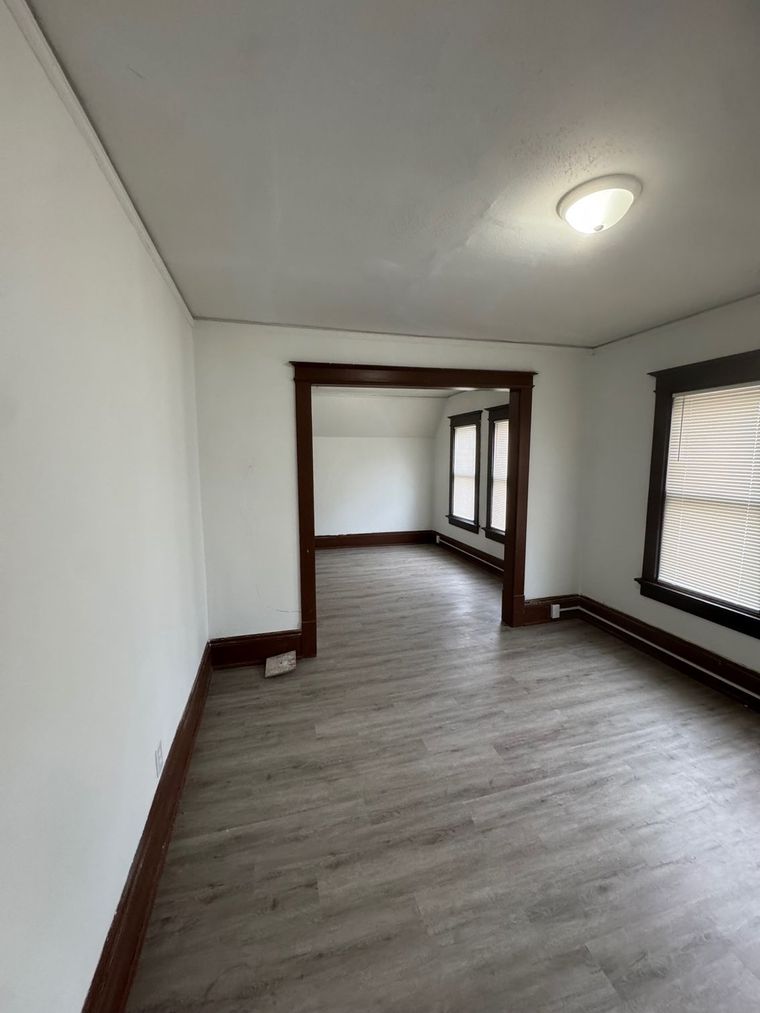 An empty room with hardwood floors and white walls.