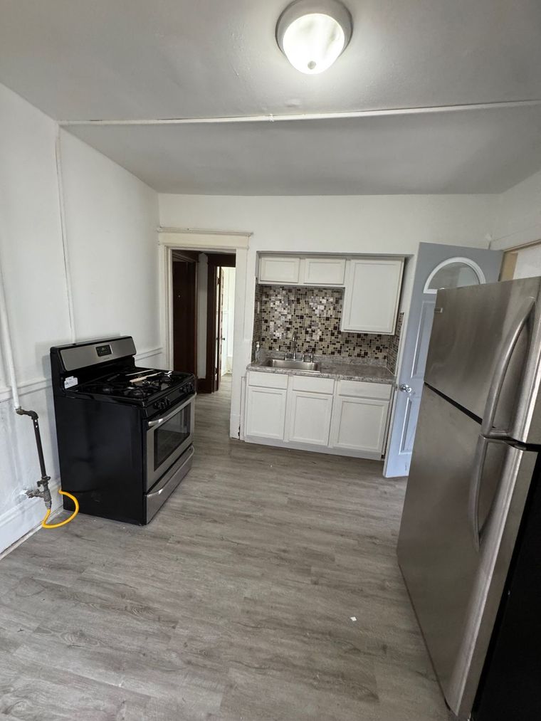 A kitchen with a stove , refrigerator , and sink.