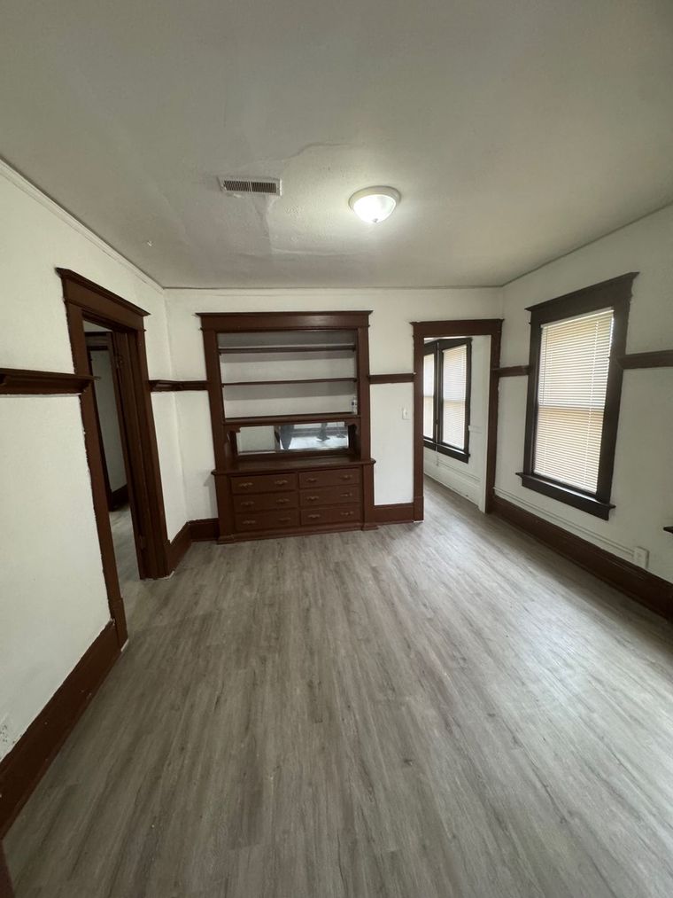 An empty living room with hardwood floors and a built in entertainment center.