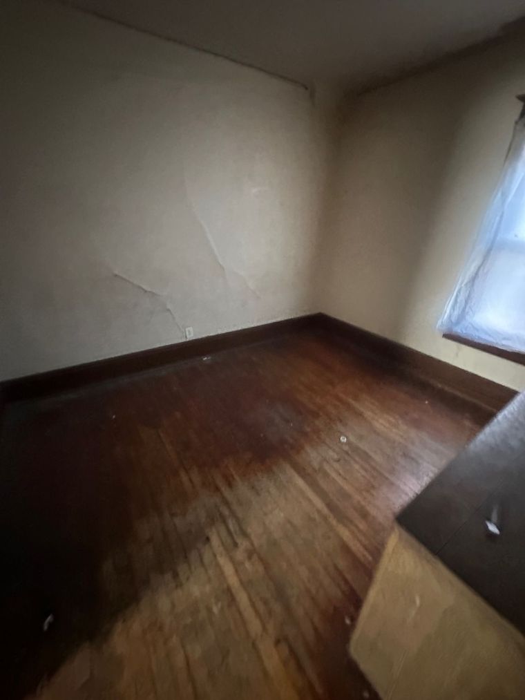 An empty room with hardwood floors and a window.