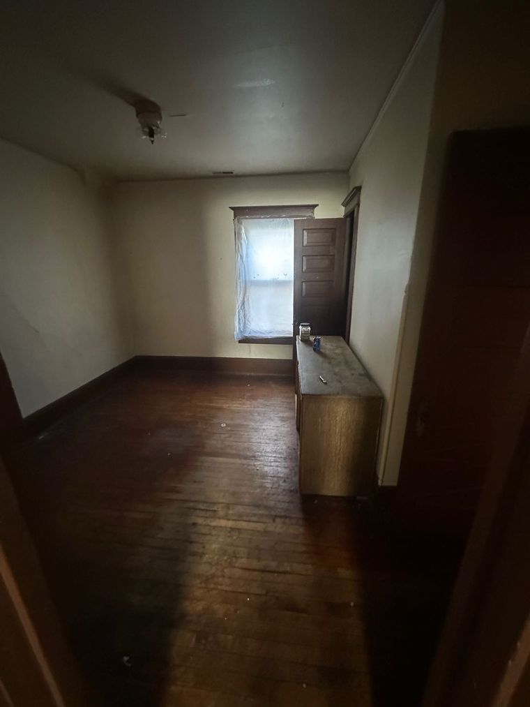 An empty room with wooden floors and a window.