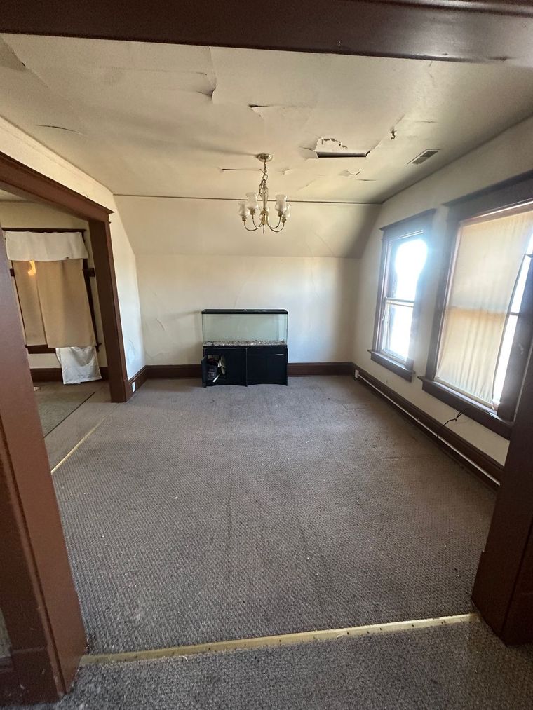 An empty living room with a chandelier hanging from the ceiling.