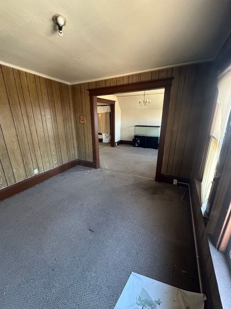 An empty room with a carpeted floor and wooden walls.
