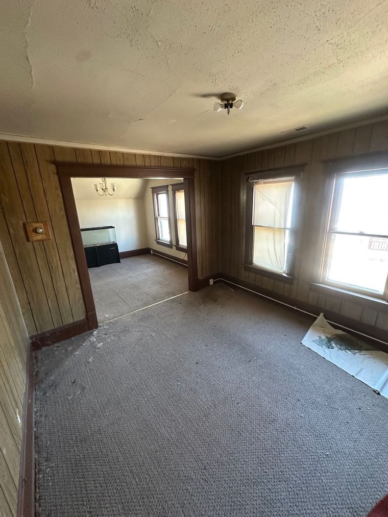 A living room with a lot of windows and a carpeted floor.
