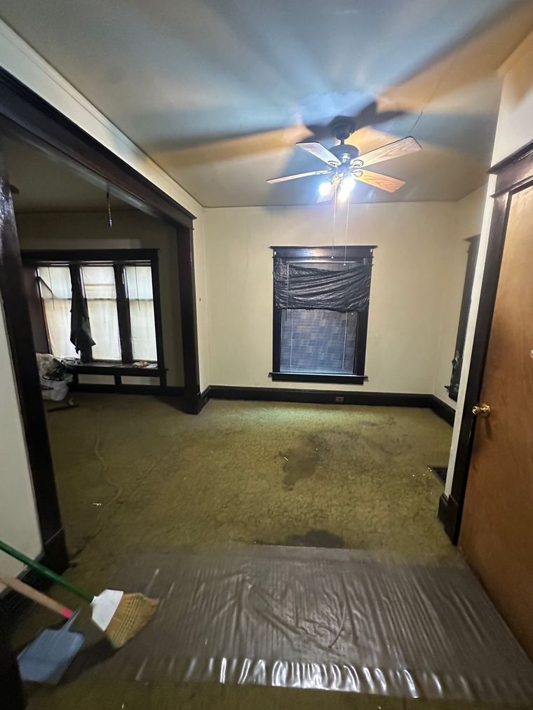 An empty room with a ceiling fan and a window.