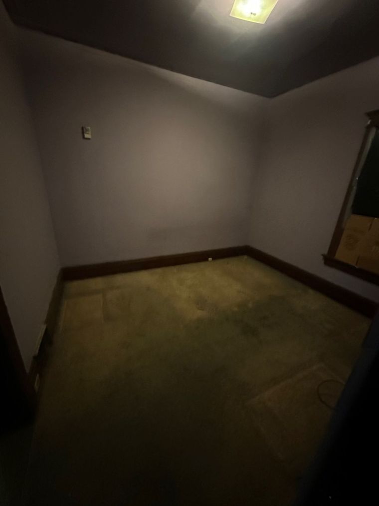 An empty room with a carpeted floor and a window.