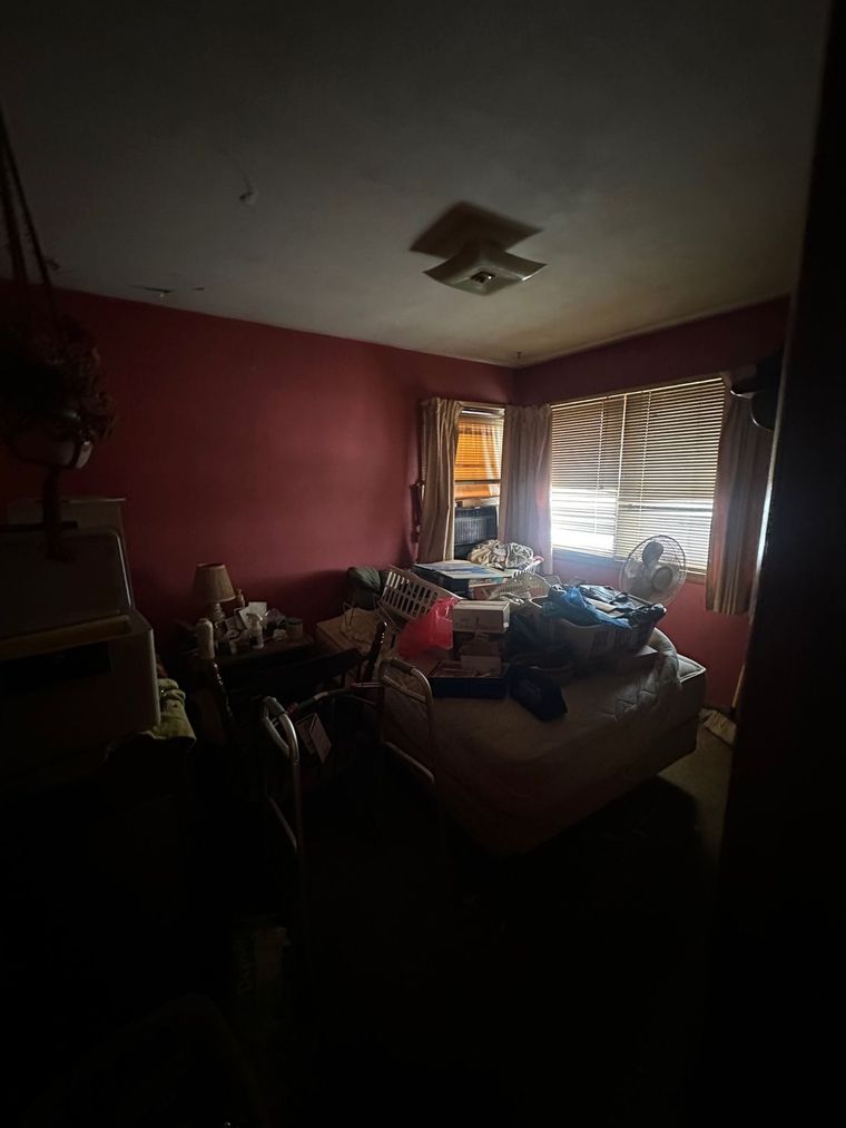 A dark bedroom with a bed and a window