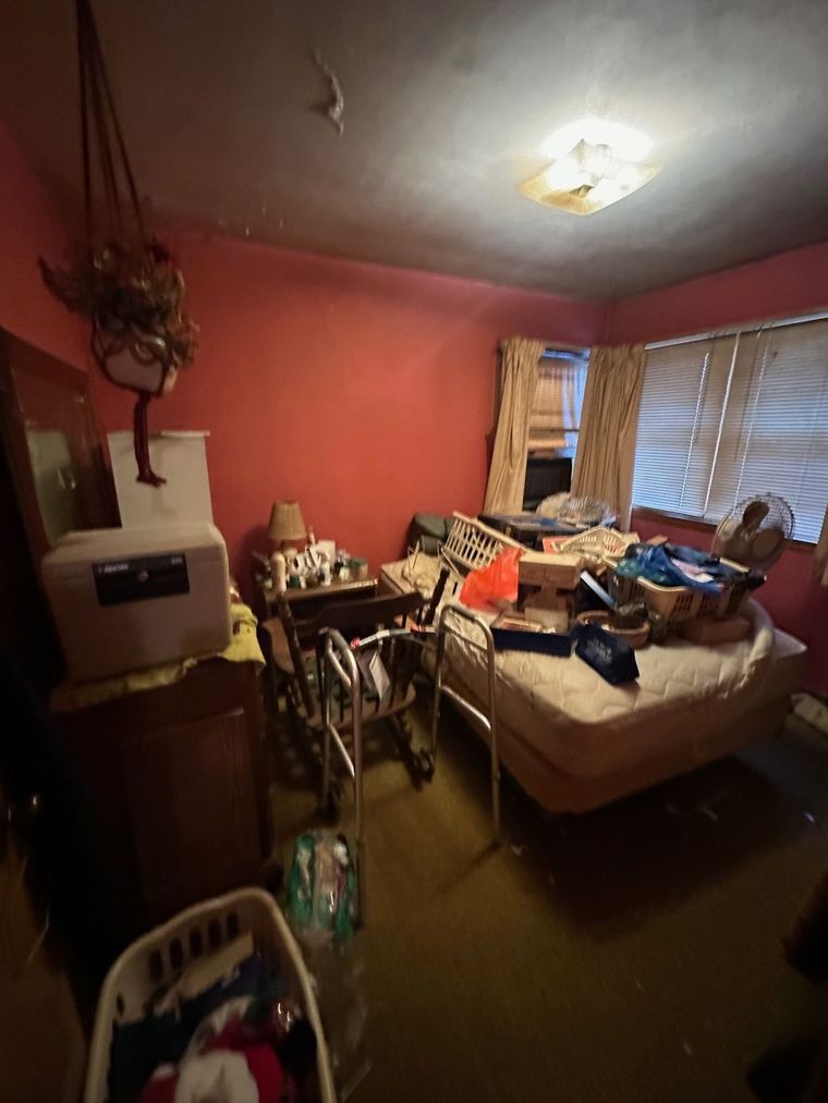 A bedroom with a bed , dresser , chairs , and a window.