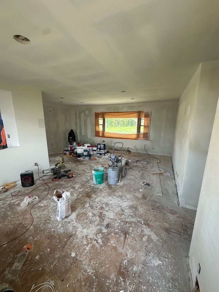 A room that is being painted with buckets of paint on the floor.