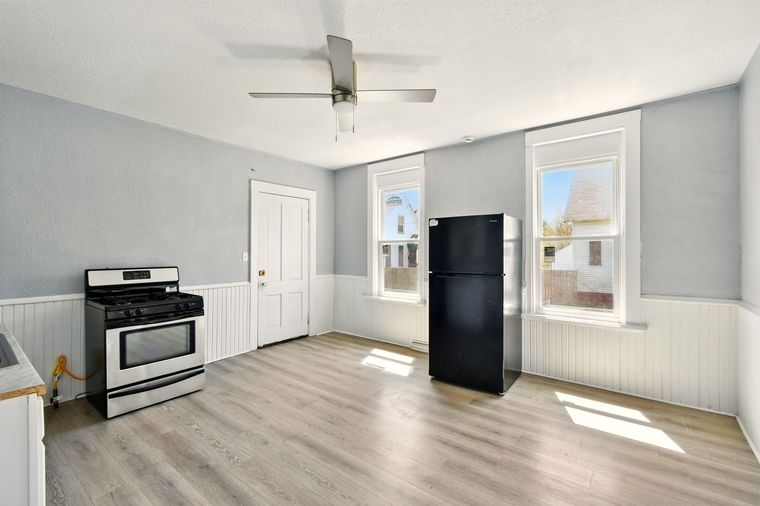 A kitchen with a stove , refrigerator , and ceiling fan.
