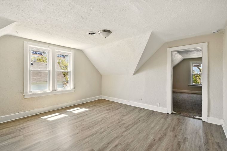 An empty living room with hardwood floors and two windows.