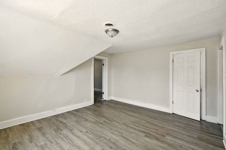 An empty room with hardwood floors and white walls.