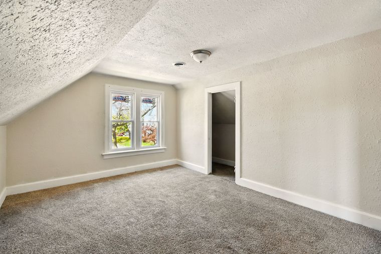 An empty room with a window and a carpeted floor.