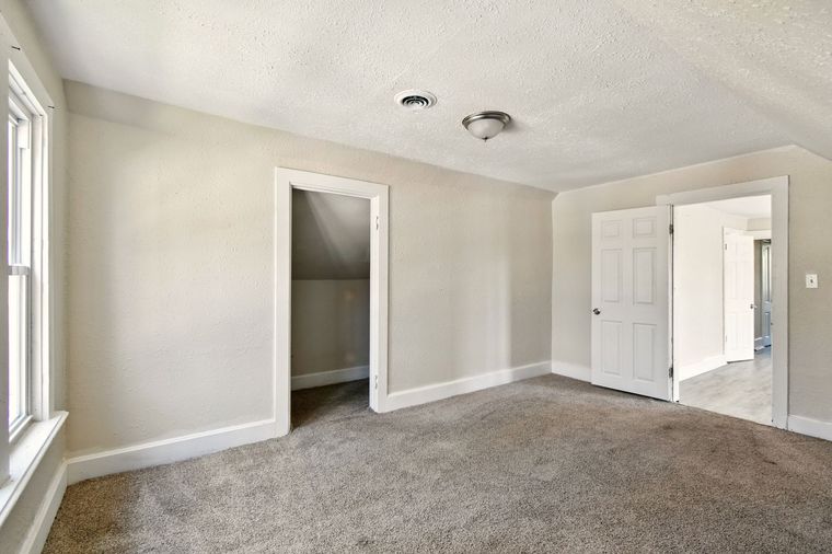 An empty room with a carpeted floor and white walls.