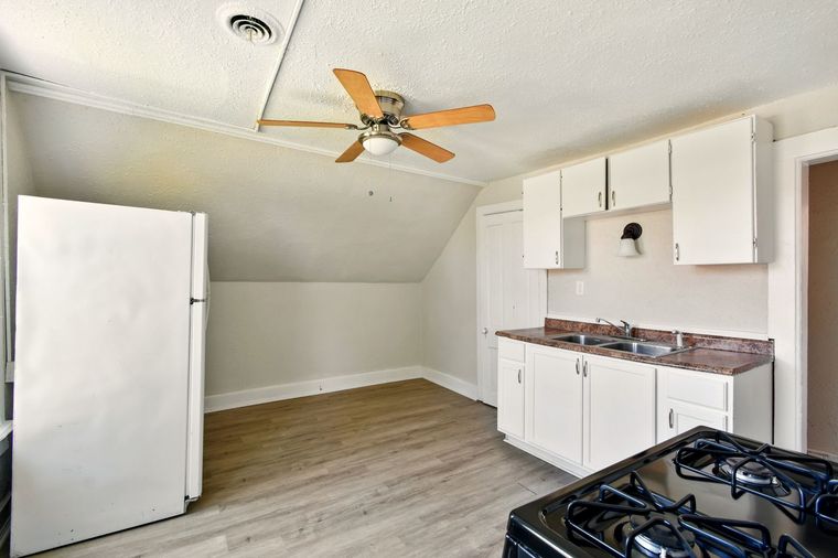 An empty kitchen with white cabinets and a ceiling fan