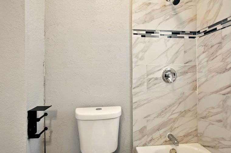 A bathroom with a toilet , tub and shower.