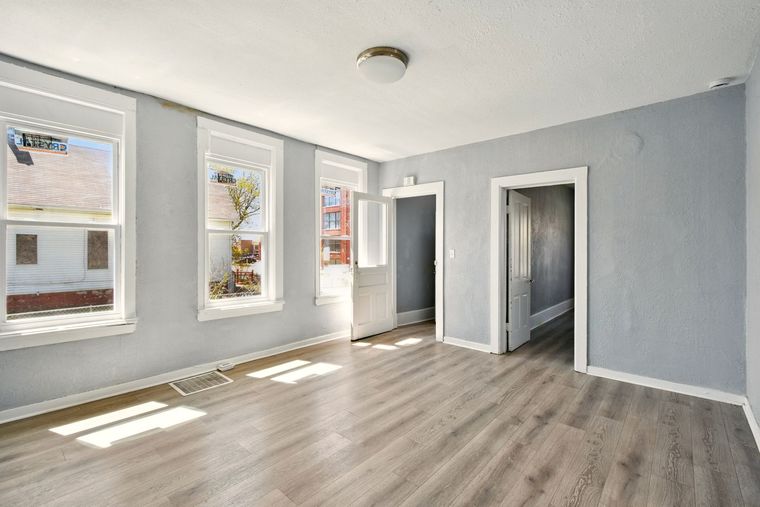An empty living room with hardwood floors and a lot of windows.
