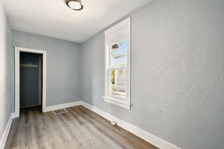 An empty room with a window and hardwood floors.