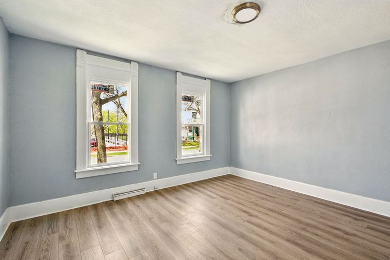 An empty room with hardwood floors and two windows.