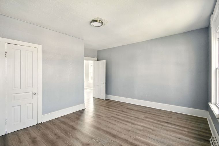 An empty room with hardwood floors , gray walls and white trim.